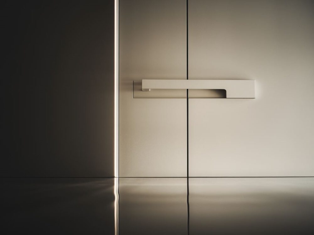 Detal białych drzwi z chromowaną klamką