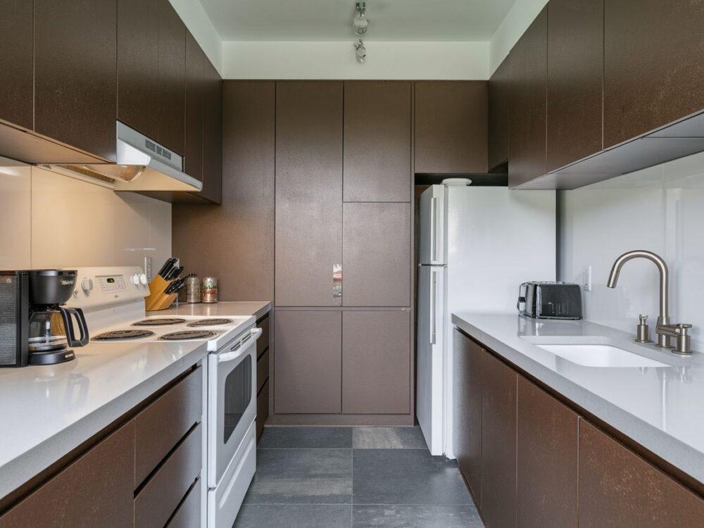 Jasny granitowy blat kontrastujący z ciemnymi meblami kuchennymi